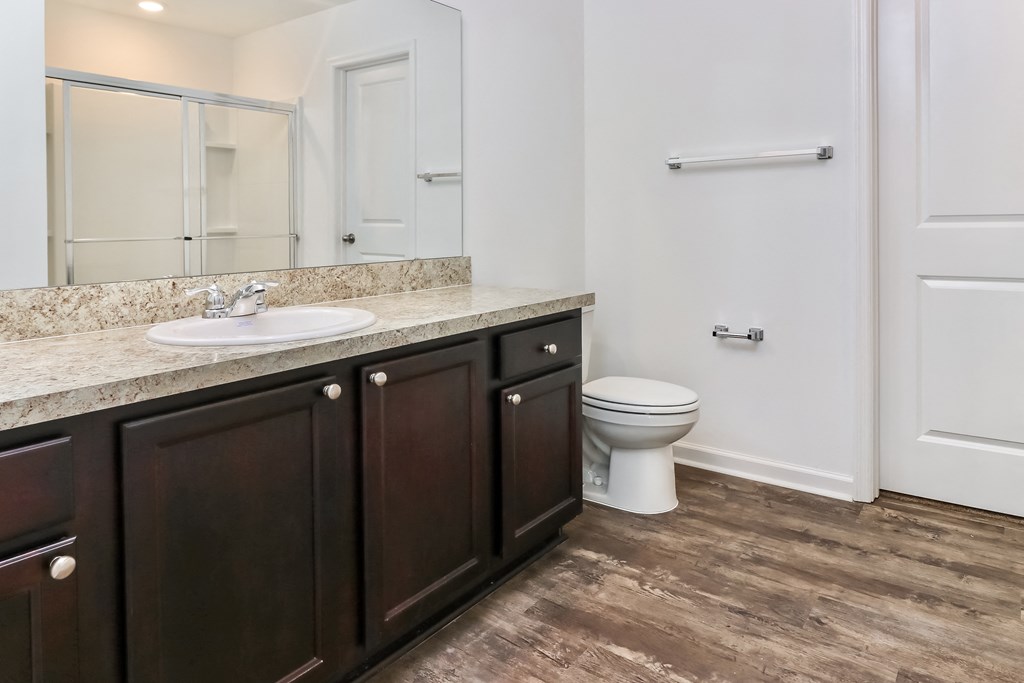 A white toilet sits in a bathroom with dark wood cabinets.