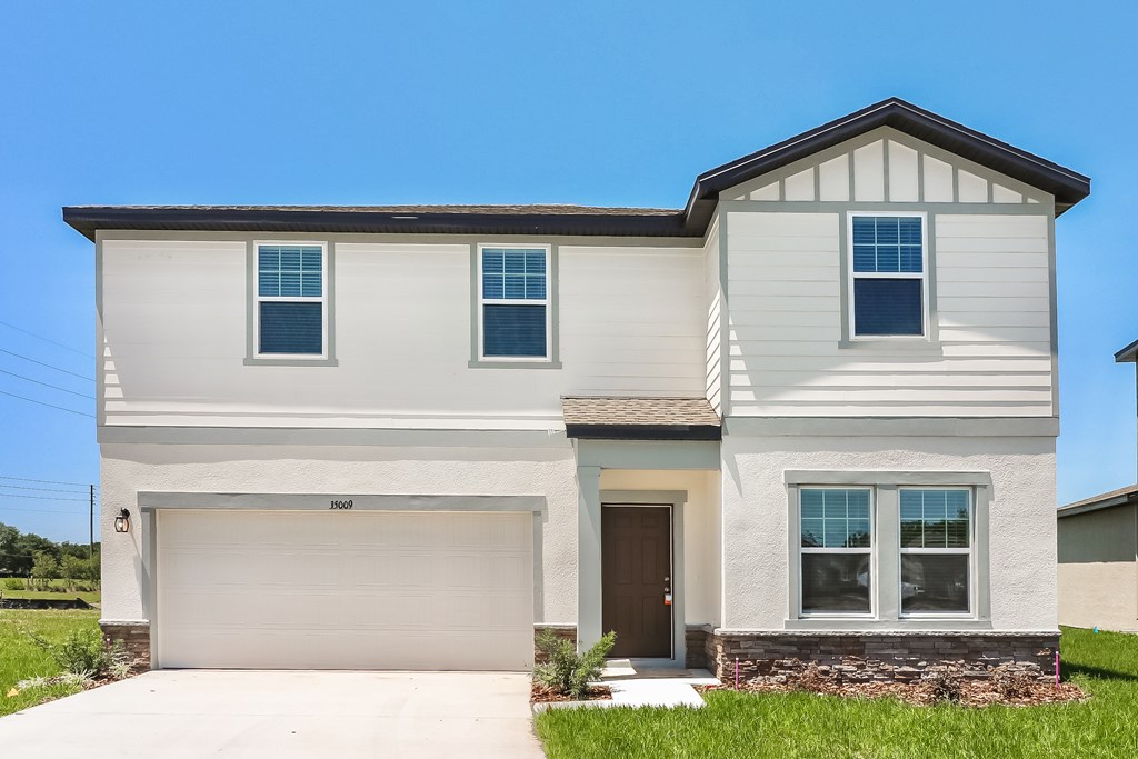 A two-story house with a garage and a brown door.
