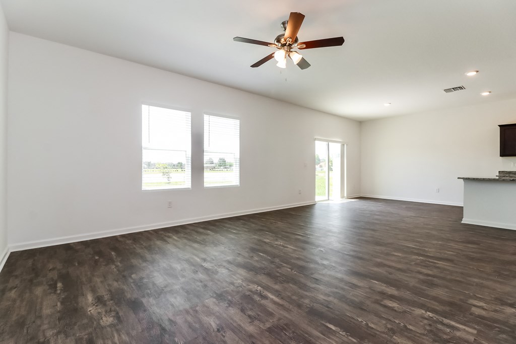 A room with a ceiling fan and wooden flooring.