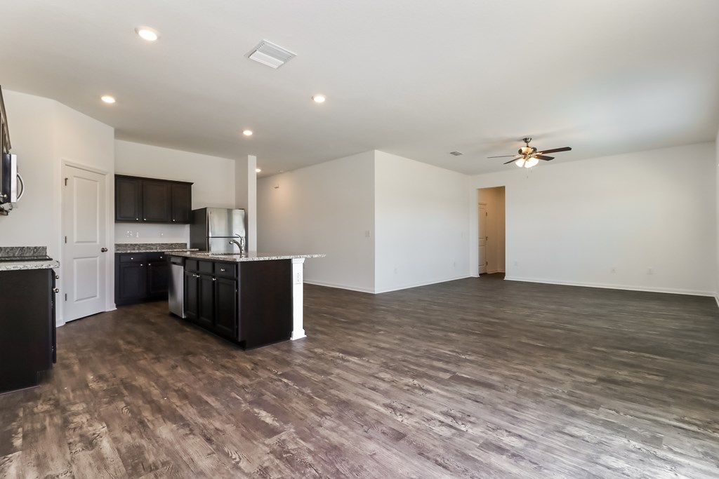A spacious room with a kitchen area and a ceiling fan.