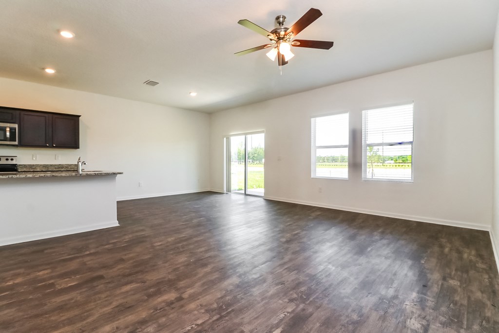 A spacious room with a ceiling fan and wooden flooring.