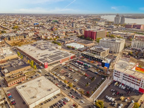 A cityscape with a mix of modern and older buildings, a river in the distance, and a clear sky.