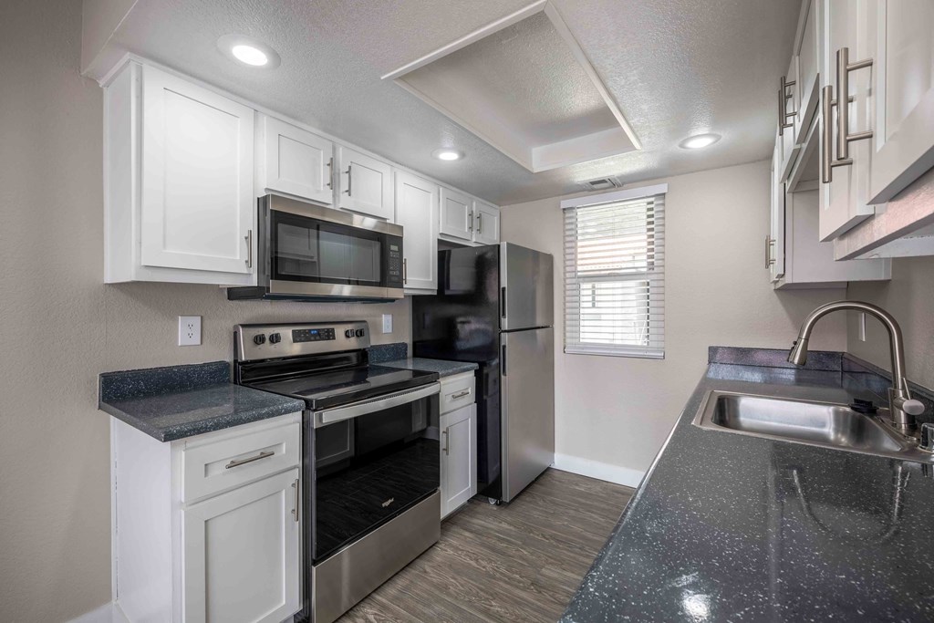 a kitchen with white cabinets and black counter tops