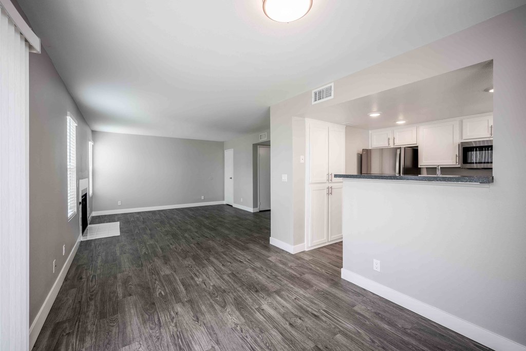 a renovated living room and kitchen with white walls and wood floors