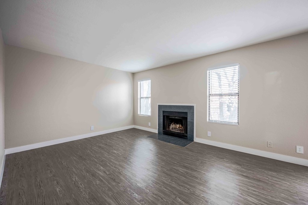an empty living room with a fireplace and wooden floors
