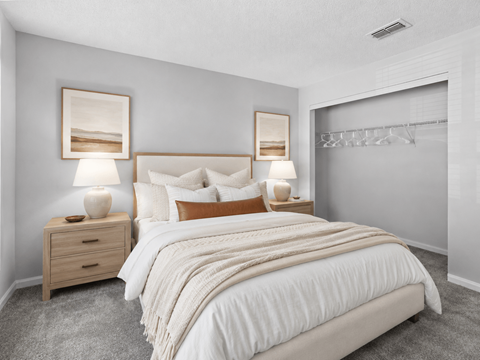 A bedroom with a large bed, two nightstands with lamps, and a wall-mounted coat rack.