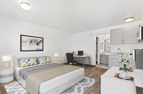a bedroom with a bed and a desk and a kitchen
