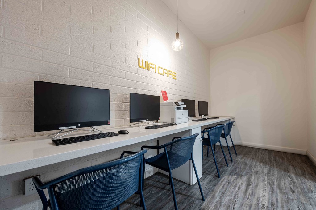 a long desk with computers and chairs in a room