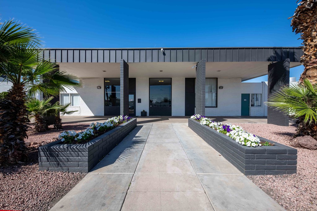 the front of the house has a long walkway and flower beds