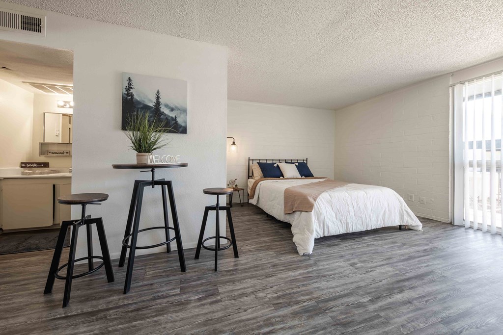 a bedroom with a bed and stools next to a kitchen