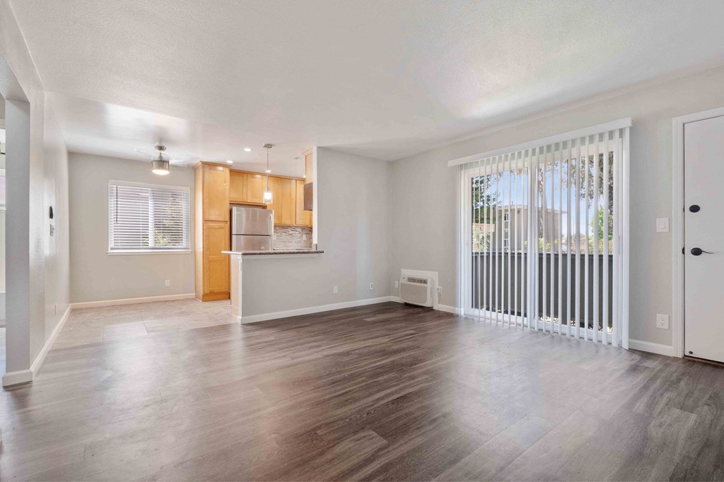 Three-Bedroom Apartments in Milpitas, CA - Spring Valley - Spacious Living Area With Access To Kitchen And Dining Area, Air Conditioning, Access To Patio, And Wood-Style Flooring.