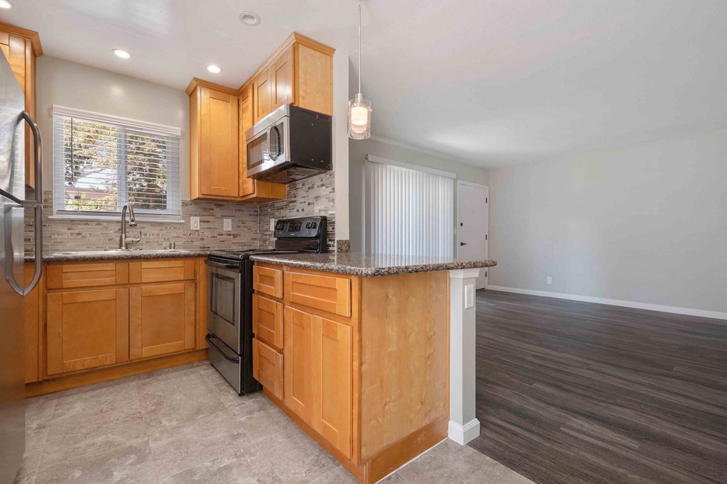 Two-Bedroom Apartments in Milpitas, CA - Spring Valley - Kitchen With Tile Backsplash, Large Window, Granite Countertops, Tile Flooring, High Ceilings With Recess Lighitng And A Hanging Light.