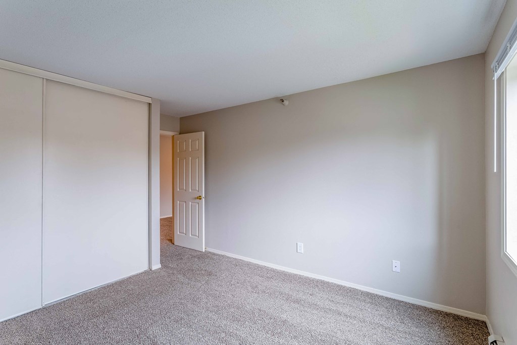 an empty bedroom with white walls and a door to a closet