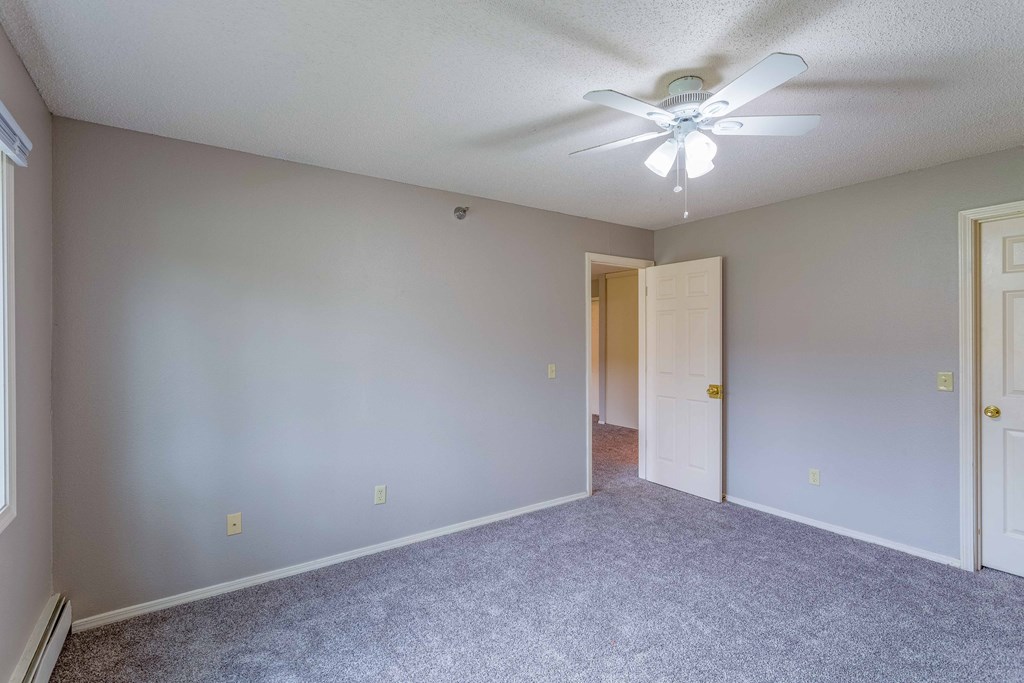 an empty bedroom with a ceiling fan and a door to a closet