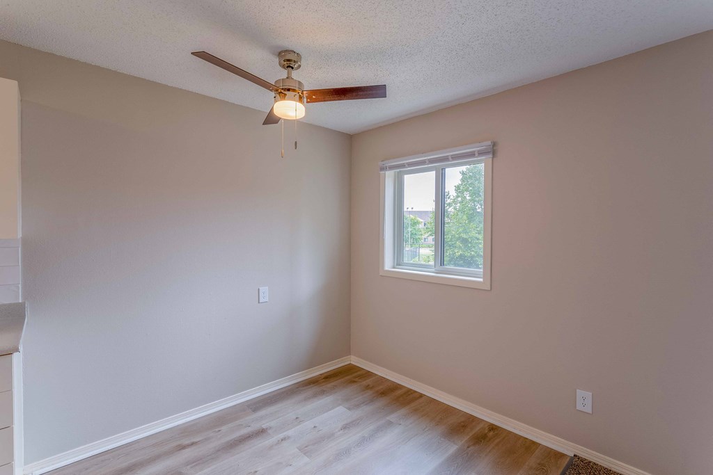 an empty bedroom with a ceiling fan and a window