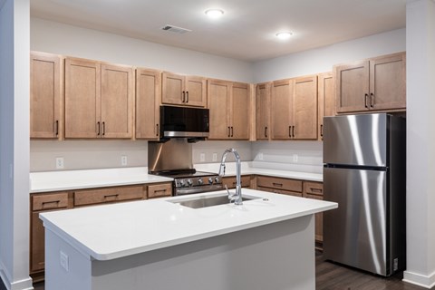 A kitchen with a white counter top and wooden cabinets.