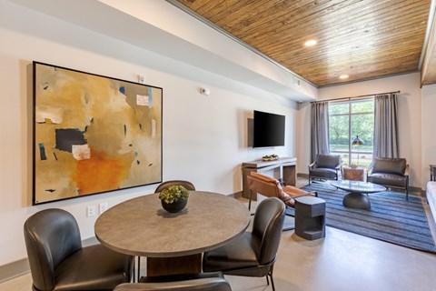 A living room with a large painting on the wall and a grey table with chairs.