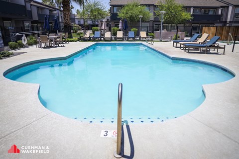 A swimming pool with a diving board and lounge chairs.