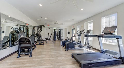 A spacious gym with a variety of equipment including treadmills, stationary bikes, and weight machines.