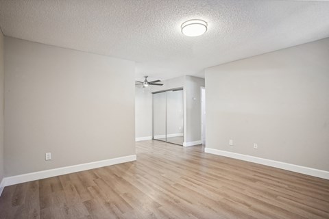 the spacious living room with hardwood flooring and white walls