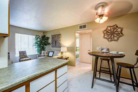 a kitchen with a bar and a living room with a table