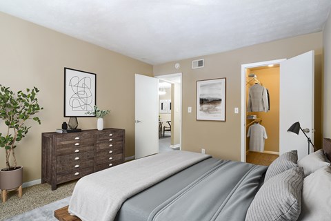 A bedroom with a large bed and a dresser with a plant on top.