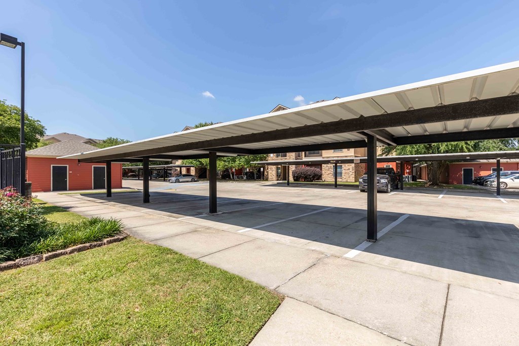 Sugar Mill Apartments in Addis, LA photo of a covered parking lot with a building in the background
