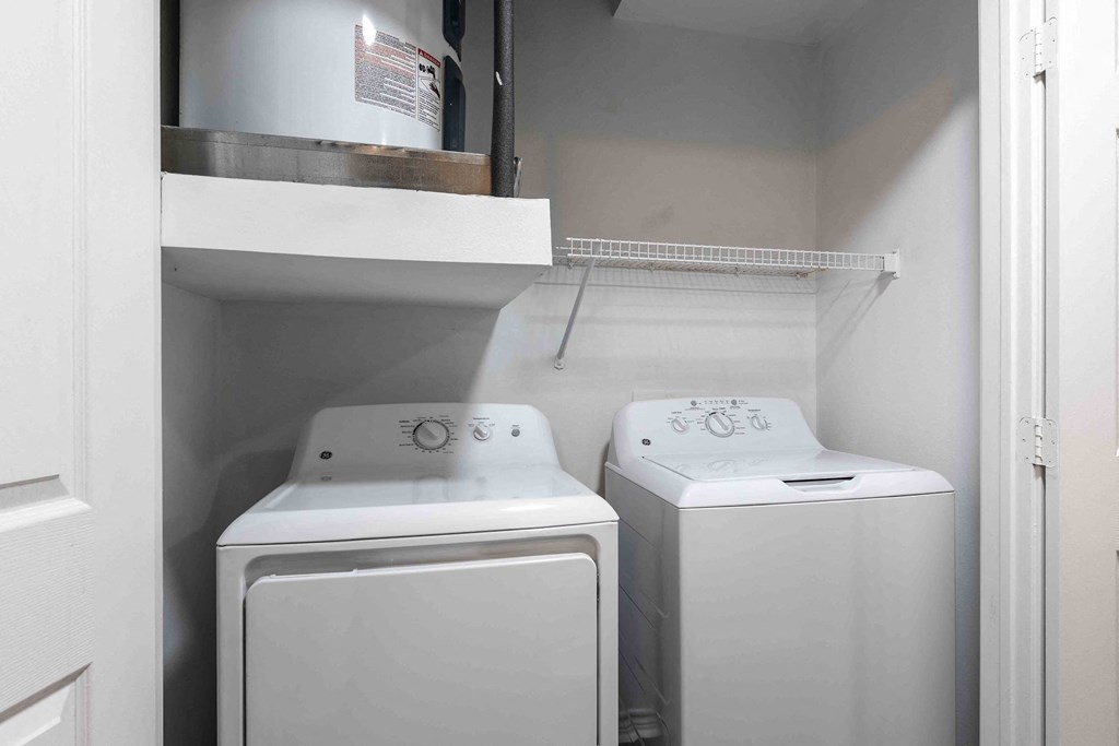 Sugar Mill Apartments in Addis, LA photo of a white laundry room with two washes and a dryer