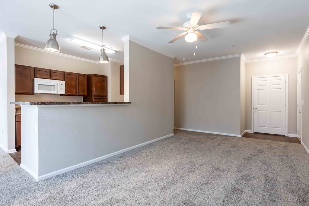 Sugar Mill Apartments in Addis, LA photo of an empty living room with a kitchen and a ceiling fan