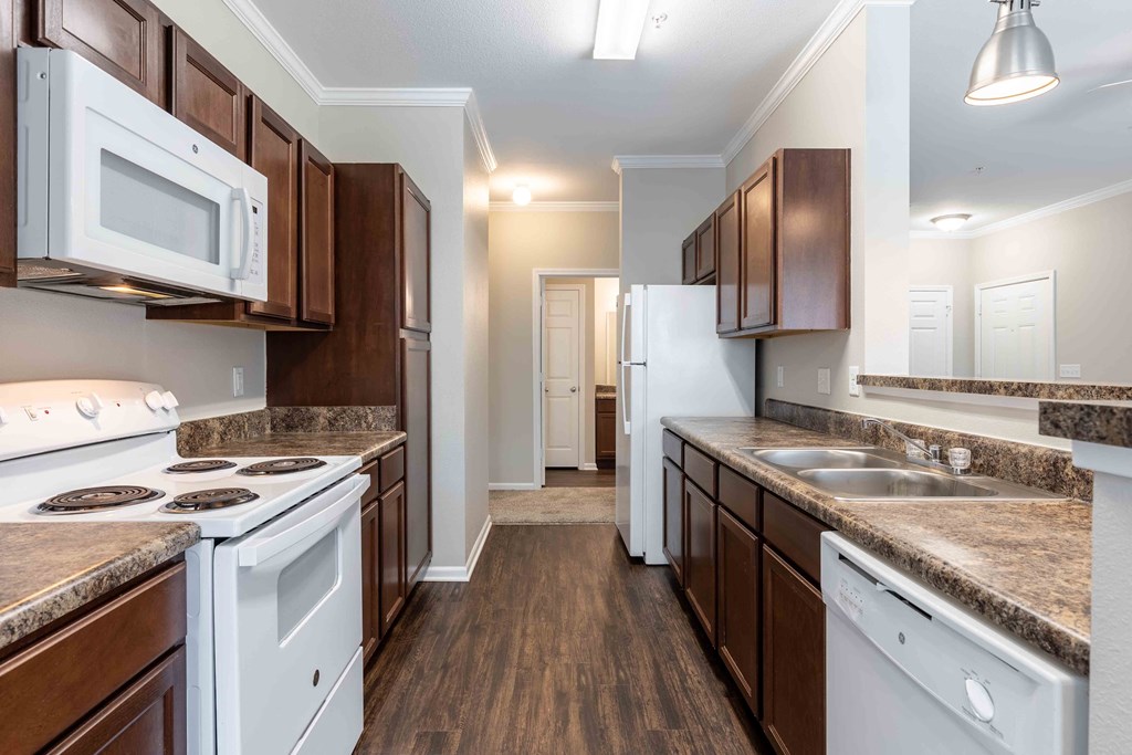 Sugar Mill Apartments in Addis, LA photo of a kitchen with white appliances and brown cabinets