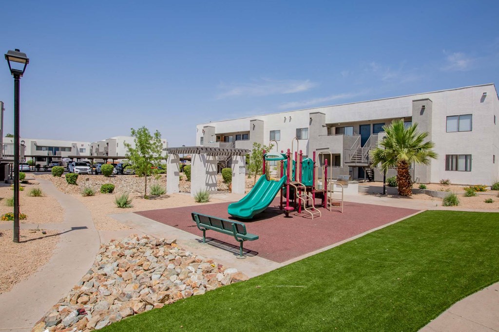 a playground in front of a building with a green slide