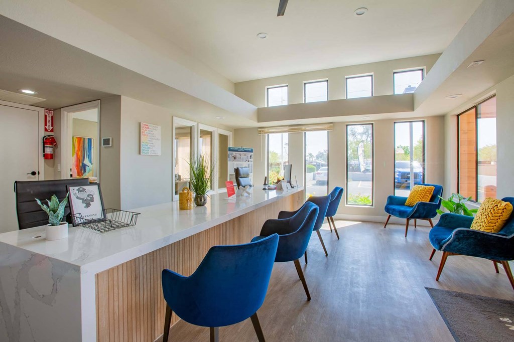 a reception area with blue chairs and a counter and windows