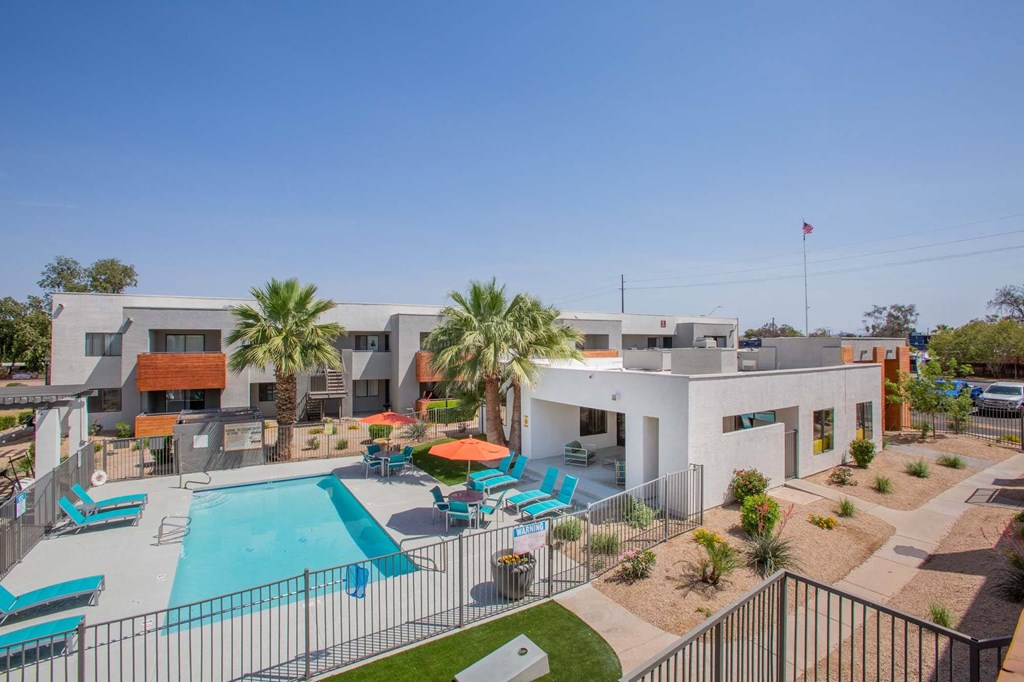 a building with a swimming pool and a patio with palm trees