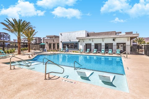 Luxurious modern apartment complex featuring a sparkling swimming pool with sun loungers and lush palm trees, perfect for relaxation and leisure at Summit on Boulder Apartments.