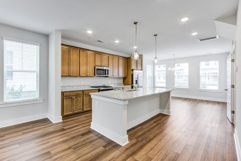an open kitchen and living room with wood flooring and a white counter top