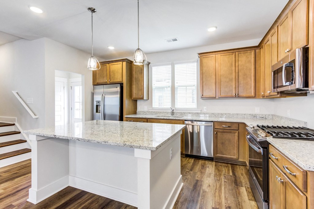 Apartments In Charleston, SC - Sumner Village - Kitchen With Vinyl Plank Flooring, Stainless Steel Appliances, Granite Countertops, Spacious Island, Large Window, And Wooden Cabinets