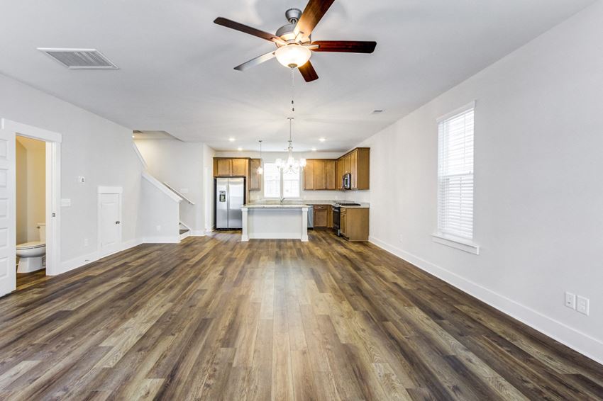 Pet Friendly Homes for Rent in North Charleston SC - Sumner Village - Open-Concept Living Room with Wood-Style Flooring, Ceiling Fan, Attached Kitchen, and a Window - Photo Gallery