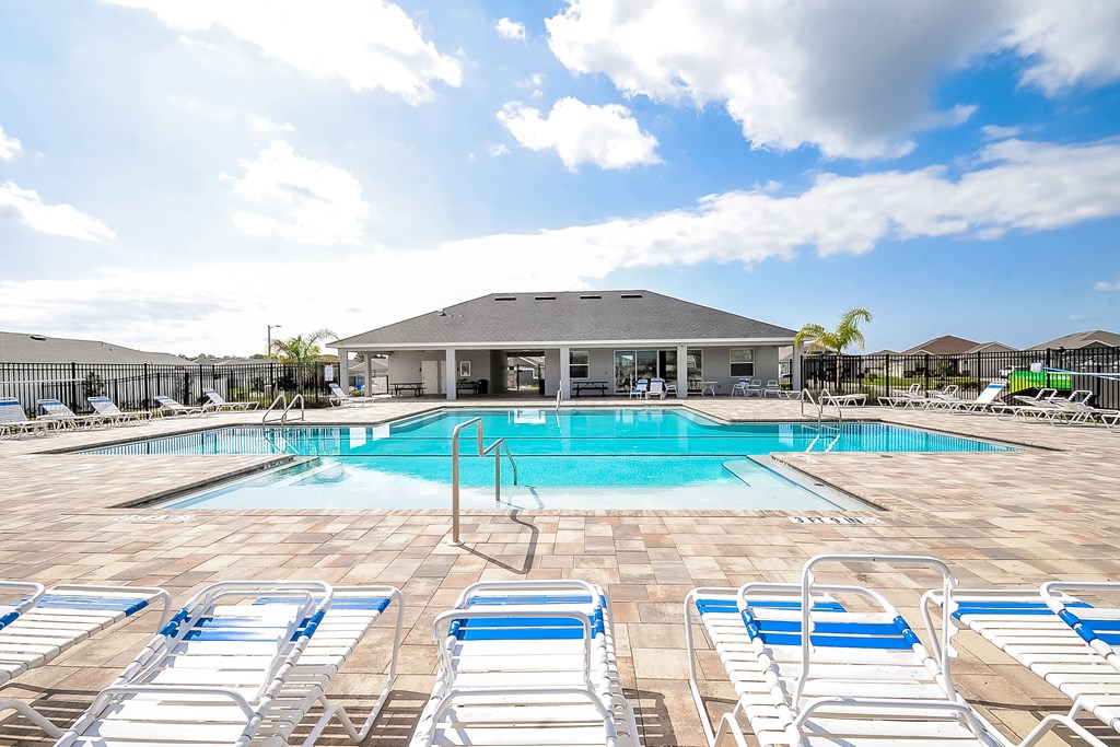 A pool with blue and white lounge chairs in front of a building.