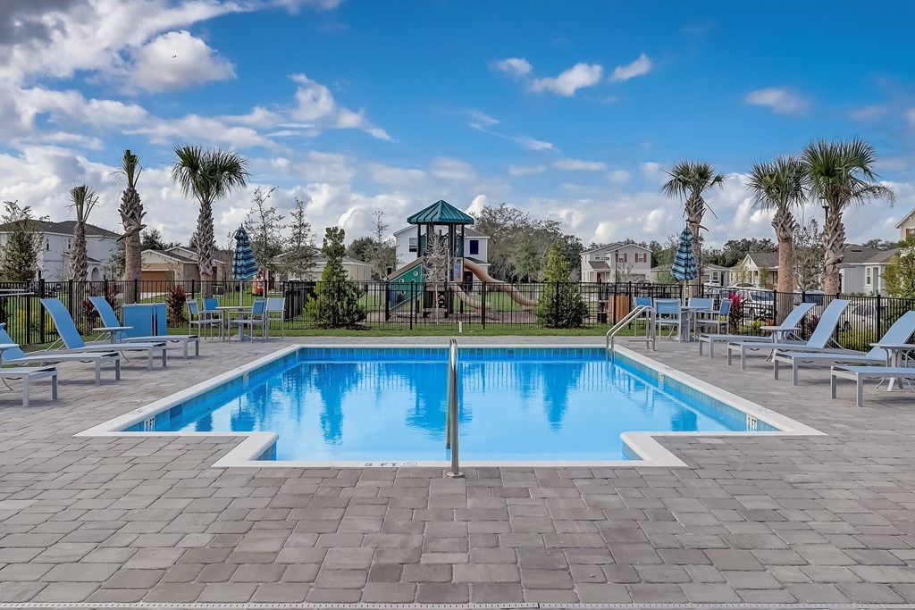 A large swimming pool surrounded by lounge chairs and palm trees.