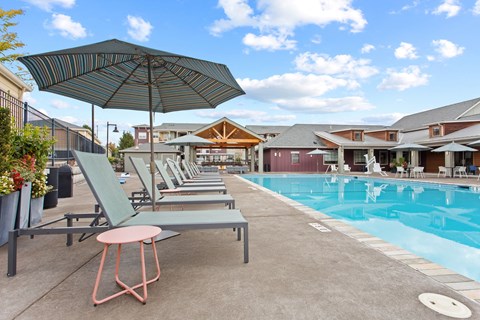 A poolside area with lounge chairs and an umbrella.