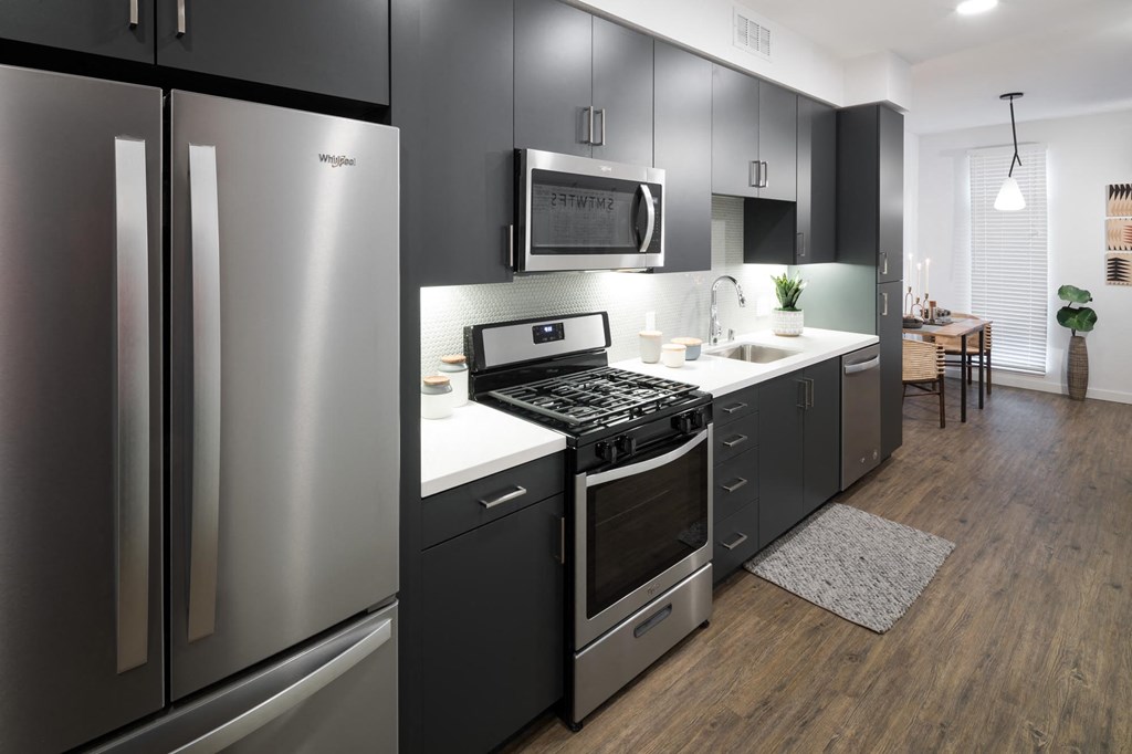 a kitchen with black cabinets and a stainless steel refrigerator