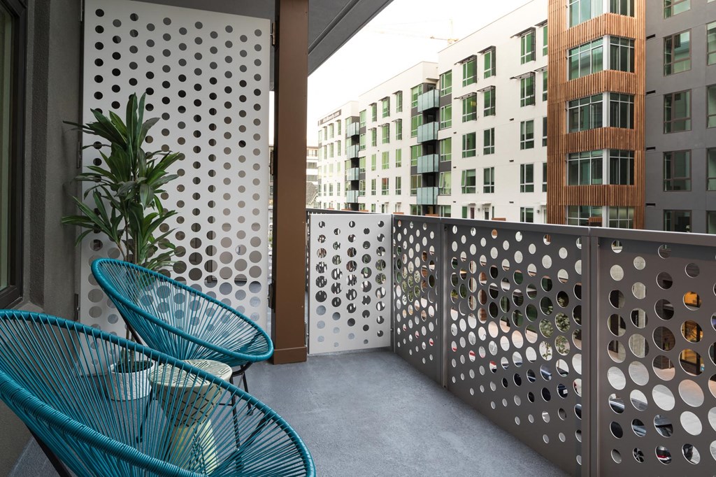a balcony with two blue chairs and a potted plant