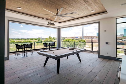 A pool table in a room with a view of the city.