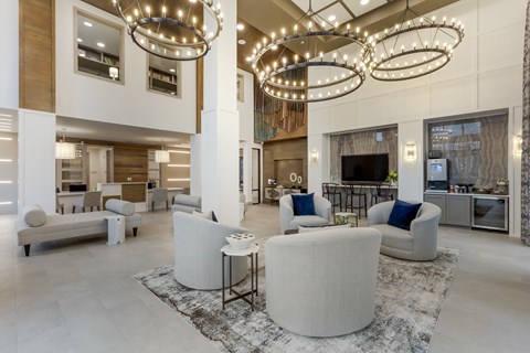 A spacious living room with a white sofa set and a large chandelier.