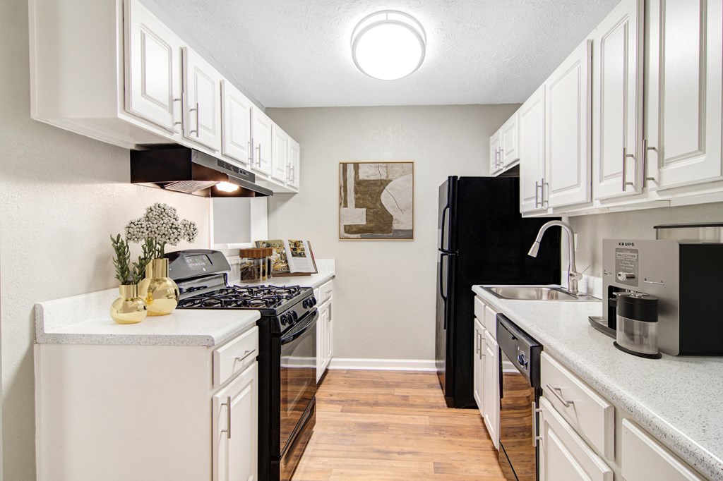 Affinitee at Stone Mountain Apartments photo of an open kitchen with white cabinets and a black refrigerator