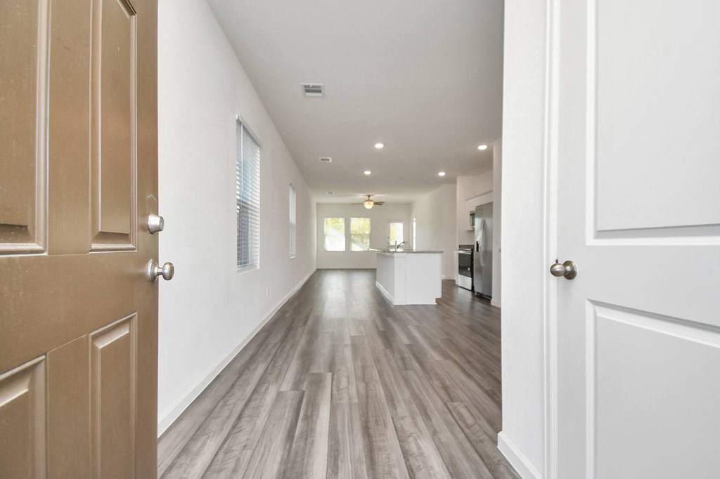 A long hallway with wood floors and white walls.
