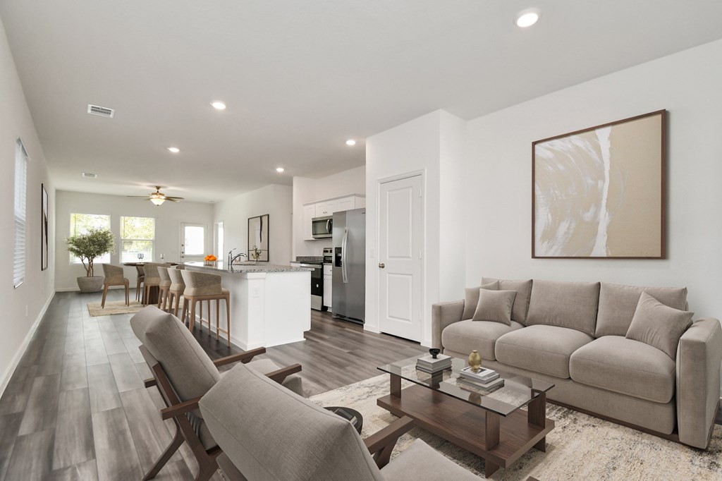 A modern living room with a grey sofa, wooden chairs, and a coffee table.