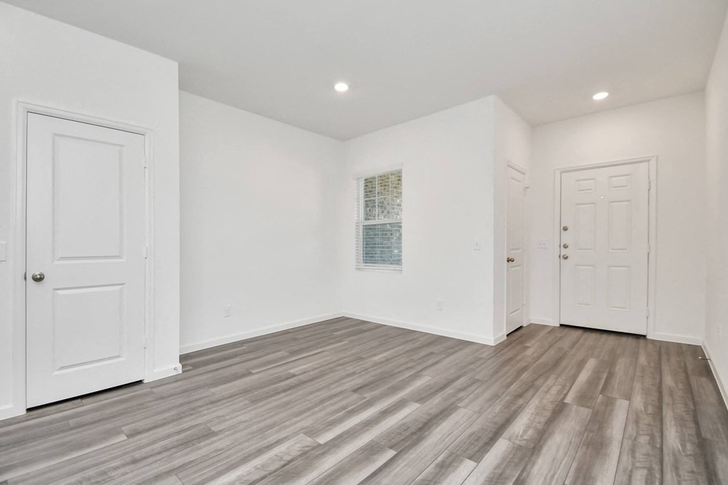 A room with white walls and wooden flooring with two doors.