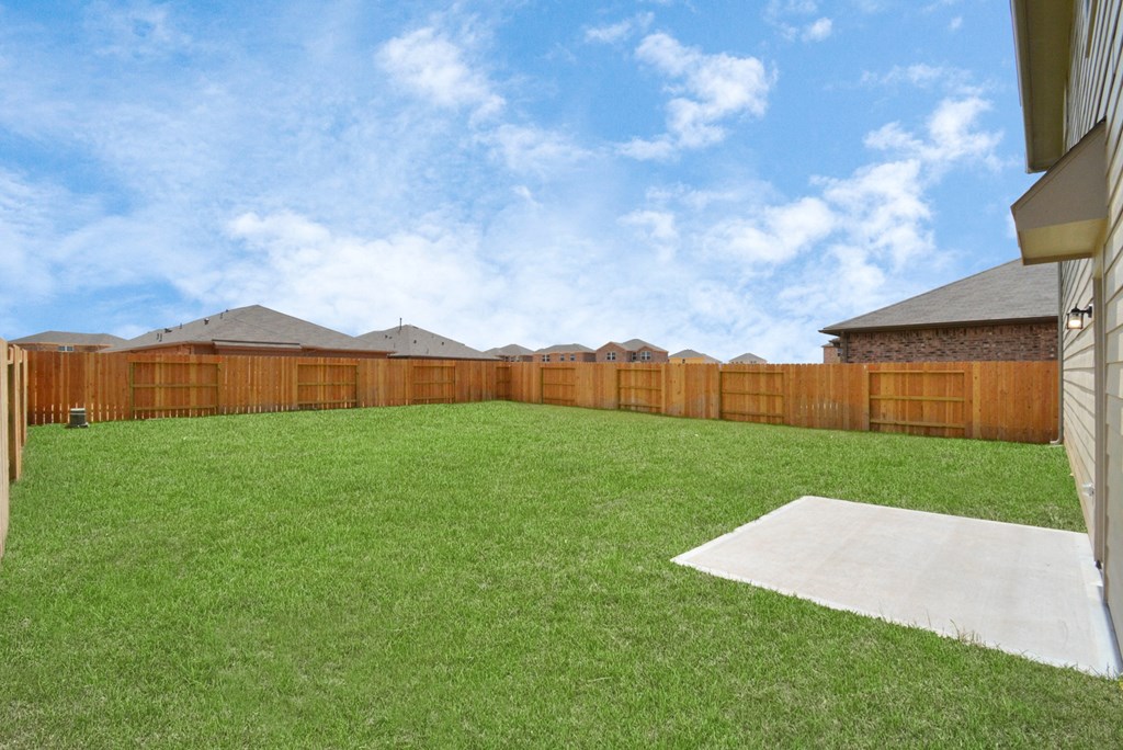 a backyard with green grass and a wooden fence