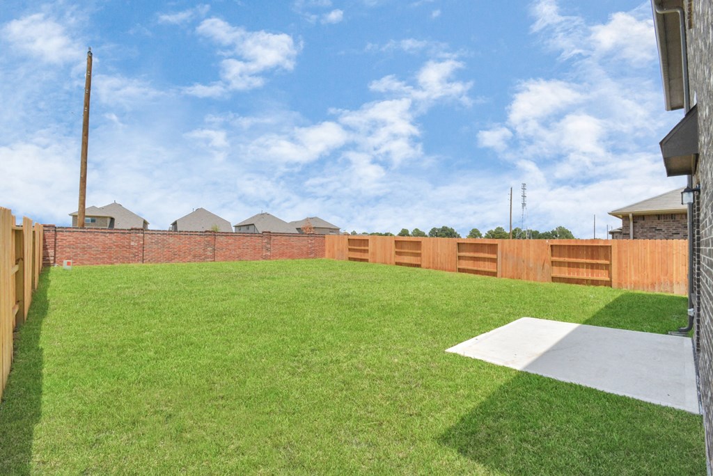 Two-BR Homes for Rent in Katy, TX - Villas at Sunterra - Backyard with Well-Maintained Green Grass and a Wooden/Brick Fence